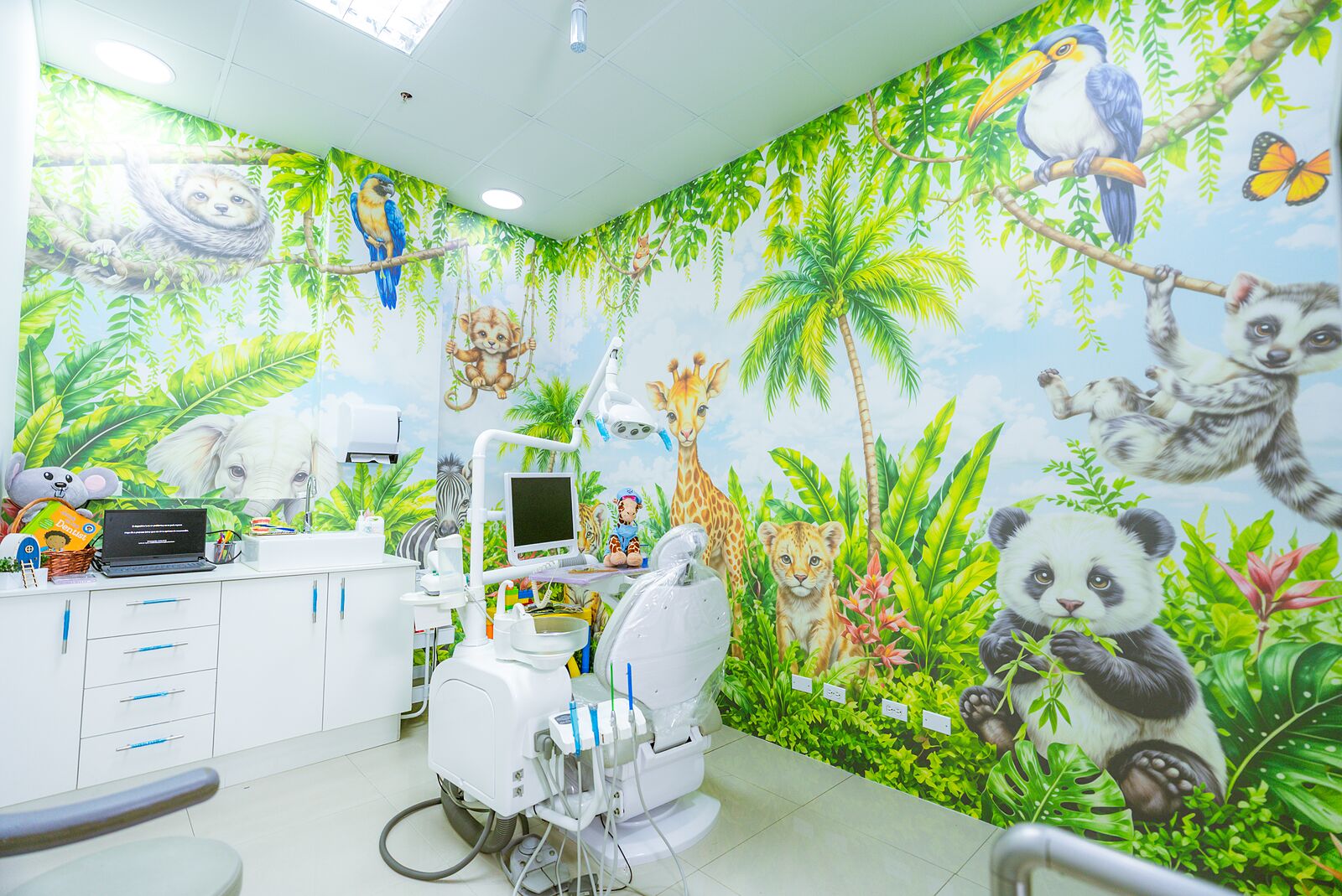 Consultorio infantil de Rubattino con un mural de selva pintado de pared a pared y el sillón dental al centro